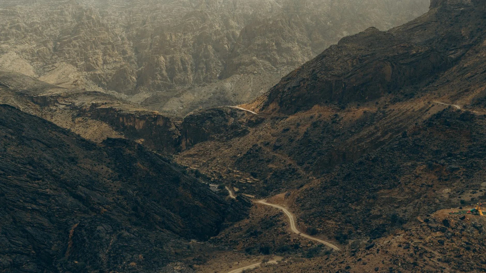 Randonneur seul sur un sentier de montagne surplombant un wadi à Oman